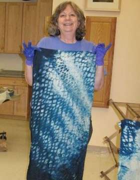 Joy-Lily, dyeing class teacher, lifts a piece of wet indigo-dyed cloth