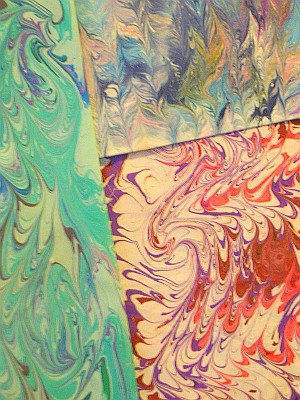 Marbled cloth samples: swirls of pink white purple and turquoise.