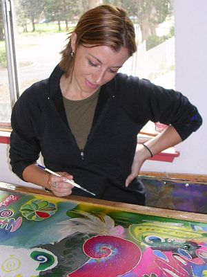 Woman with hand on hip draws with wax on fabric